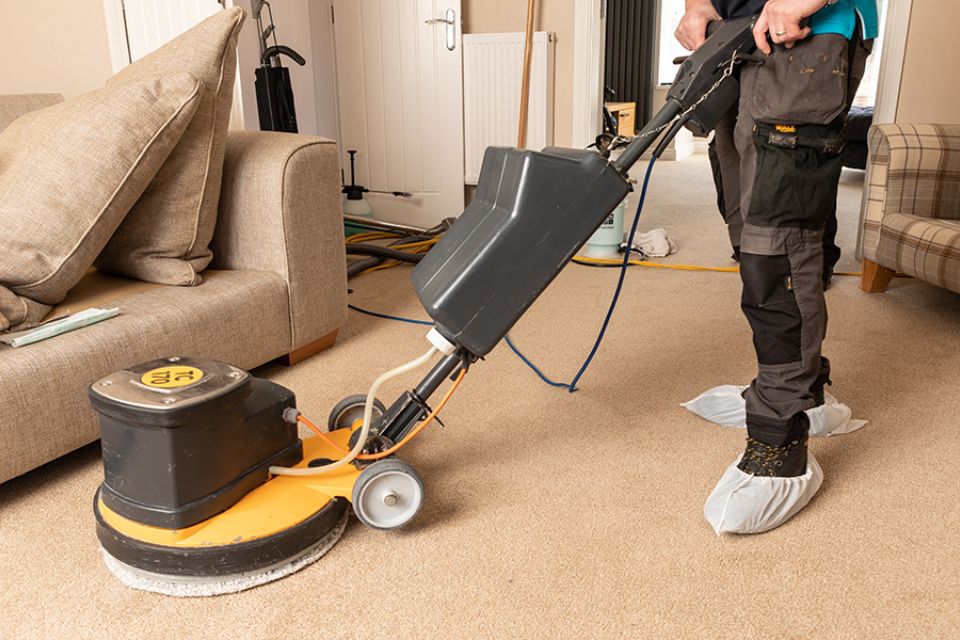 A man uses a carpet cleaner in a living room, highlighting a carpet cleaning service located in San Jose, CA.