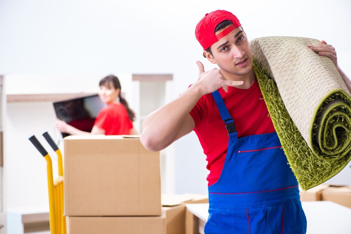 A man in overalls holds a roll of carpet, ready for professional installation.