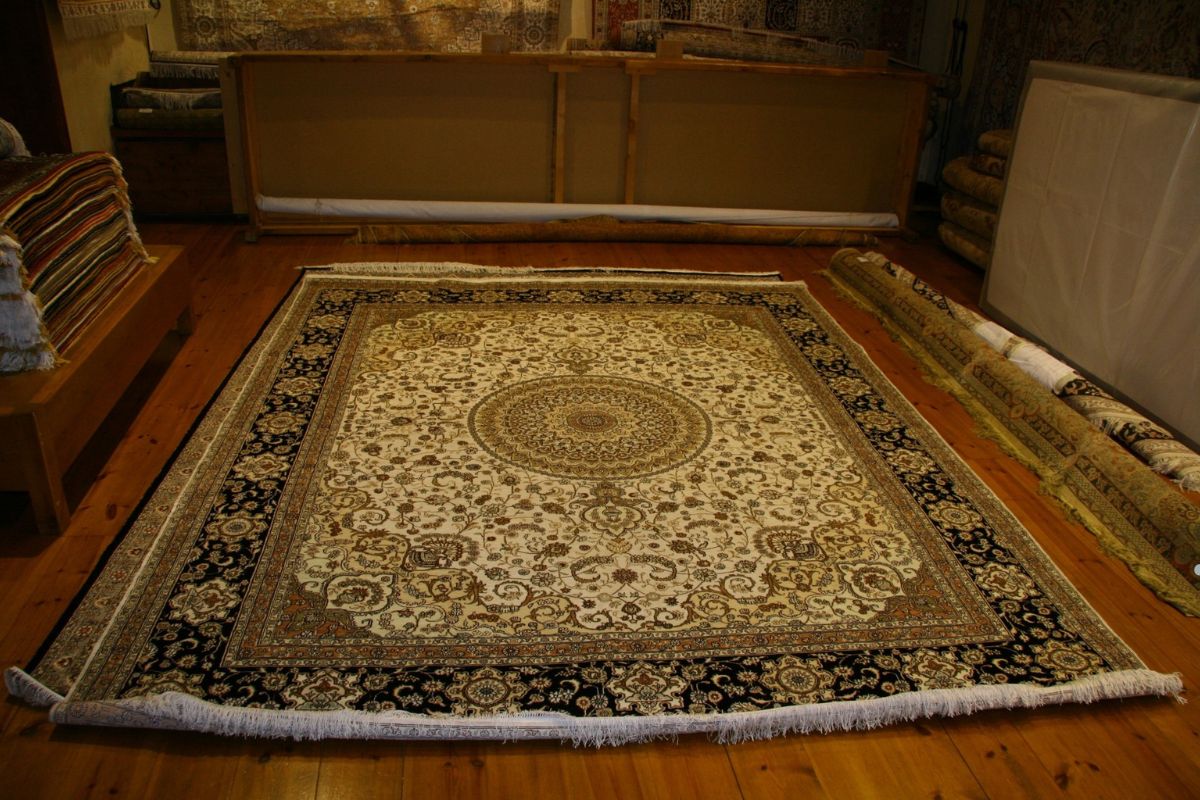 A large oriental rug on the floor of a room, showing signs of water damage affecting its fibers. 