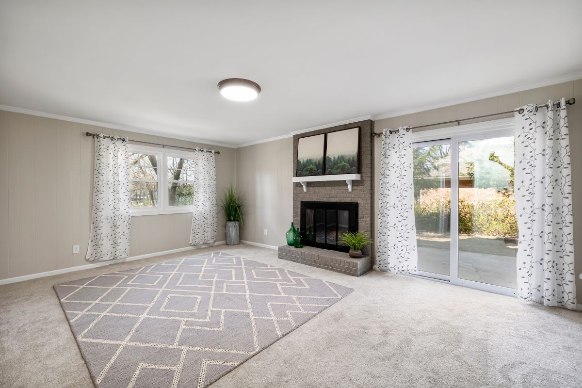  living room featuring a fireplace, sliding glass door, and visible downspouts indicating potential carpet damage. 